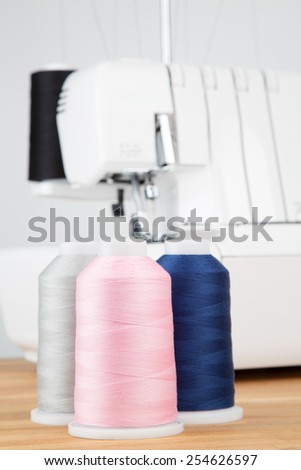 Sewing threads on wooden table with sewing machine in background. Short depth of field.