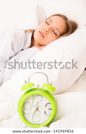 Beautiful woman sleeping with alarm clock on the bed