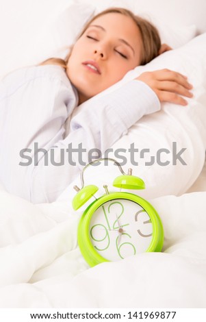 Beautiful woman sleeping with alarm clock on the bed