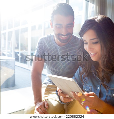 Fashion couple using a tablet with sunbeams and lens flare
