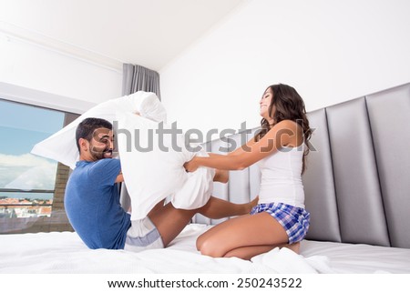 Funny couple fighting with pillows in bed