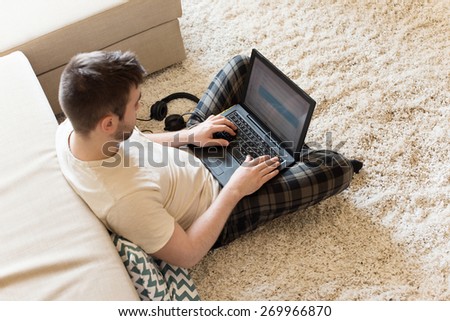 Man sitting on the floor typing on laptop - focus on laptop
