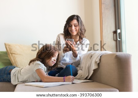 Little girl painting in the living room while mom is on internet