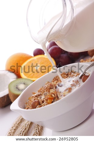 Milk pouring onto muesli and fruits as background