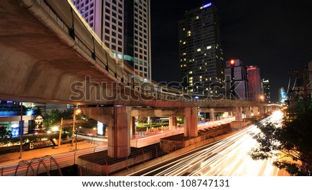 BANGKOK - JUL 07: Light trails on elevated rail and street at Sathorn business center on July 07, 2012 in Bangkok, Thailand.  Elevated rails cover business, resident, and tourist areas by 32 stations.