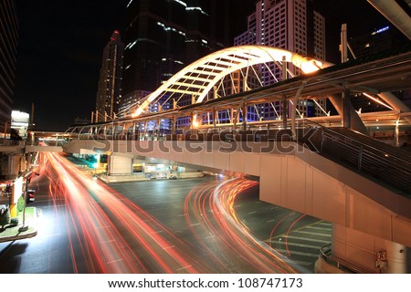 BANGKOK -JUL 07: Light trails on Sathorn-Narathiwas Intersection under public sky walk in Bangkok, Thailand on July 07, 2012. Sky walk is for transit between Bangkok sky train and rapid bus systems.