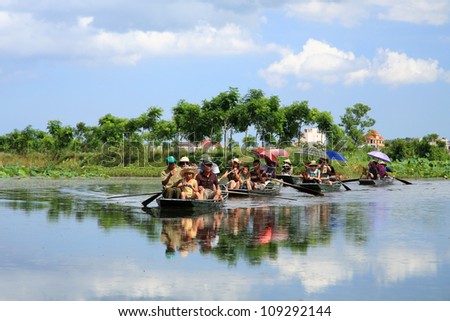 NINH BINH, VIETNAM - JULY 21: Unidentified travelers are on boats to visit rice fields , three caves, and limestone mountains along the Ngo Dong river at Tam Coc in Ninh Binh, Vietnam on July 21,2012.