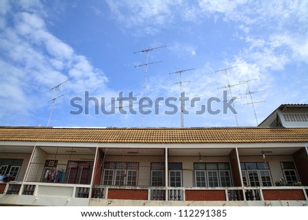 Bunch of obsolete high TV aerial antennas mounted on the roof against a blue sky