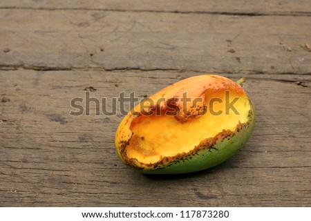 rotten ripe mango bitten by insects on wooden board