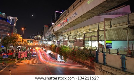 BANGKOK-MAR 16:Light trail on Rama I street with public sky walk at Pathumwan junction on March 16, 2013 in Bangkok, Thailand. Sky walk can link to BTS sky train station named National stadium.
