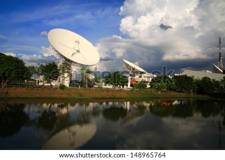 Large broadcast radars or satellite dishes with reflection on the pond