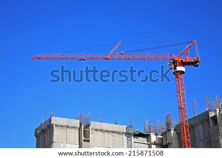 Red crane at Construction site against blue sky
