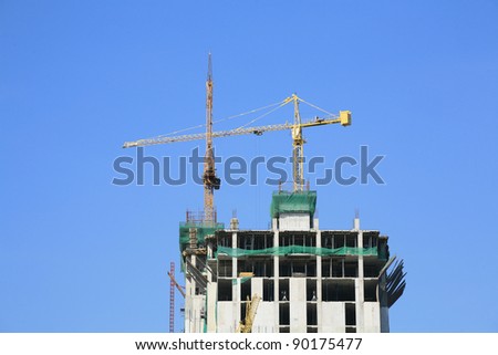 Industrial construction: building of top level skyscraper by yellow crane