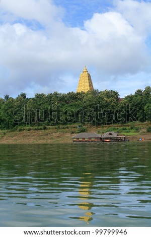 Ornament:  beautiful landscape of gold Buddhagaya pagoda and wooden raft house on the river at Sangklaburi, Thailand