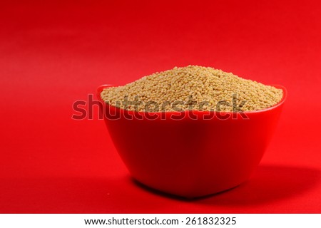 yellow mustard seeds in red bowl isolated on red background