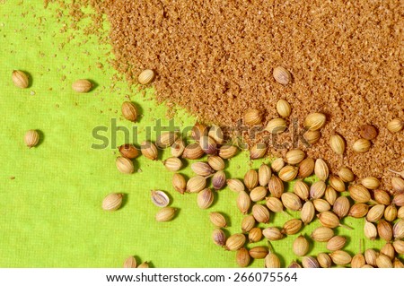 Coriander seeds and Powdered coriander on green background