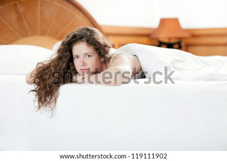 Young seductive pretty girl sleeping on a soft bed. Her hair fell down.