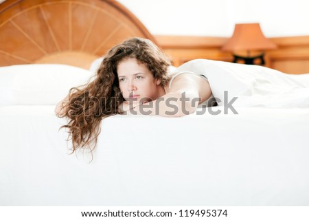 Young seductive pretty girl lying on a soft bed. Her hair fell down.