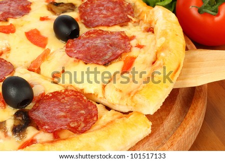 Pizza on wooden round board with tomato on background