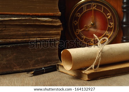 Retro composition with books, clock, paper and pen on wooden background