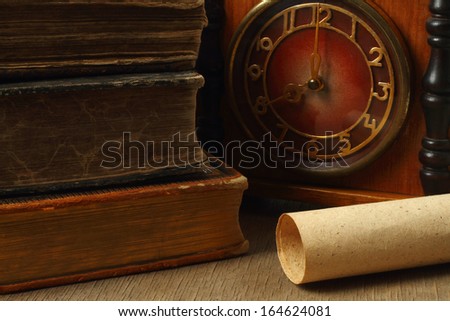Retro composition with books, clock and paper on wooden background