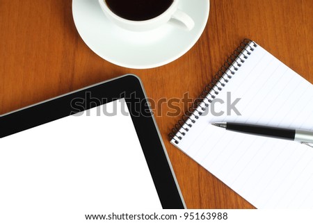 Touch screen device, notepad, pen and cup of coffee on wooden background