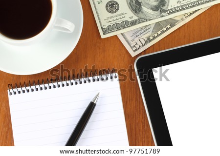 Touch screen device, notepad, pen, money and cup of coffee on wooden background