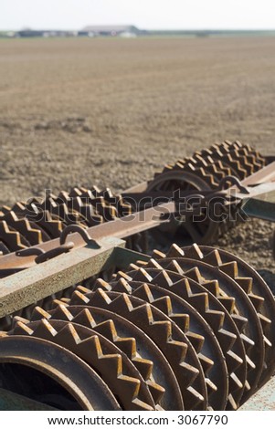 Agricultural tool with wheels with teeth resting on the cultivated land.