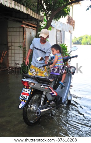 CHACHOENGSAO, THAILAND - OCTOBER 29: Father and unidentified son on a motorbike in the rising tide from Bangpakong River  in October 29, 2011 in Chachoengsao, Thailand.