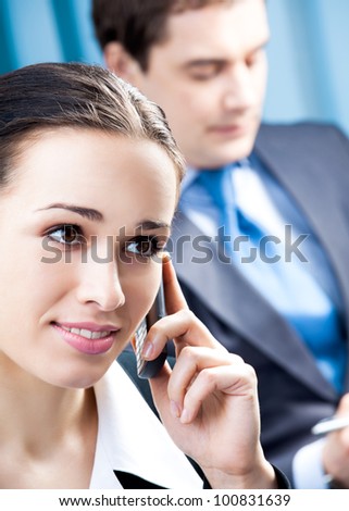 Happy smiling cheerful young business woman with cellphone at office