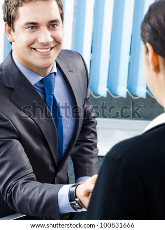 Two happy smiling cheerful businesspeople or business man and client handshaking at office