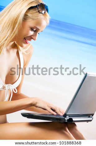 Young happy smiling woman with laptop, working, chatting, searching or walking by mobile internet on beach