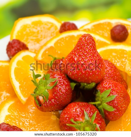 Plate with orange, strawberry and raspberry, outdoors