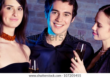 Two young beautiful women and man with champagne at party