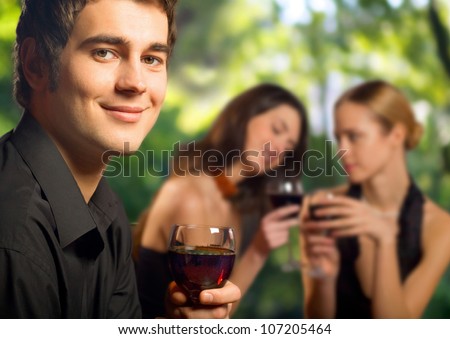 Young happy smiling man with a glass of red wine celebrating at restaurant, bar or cafe