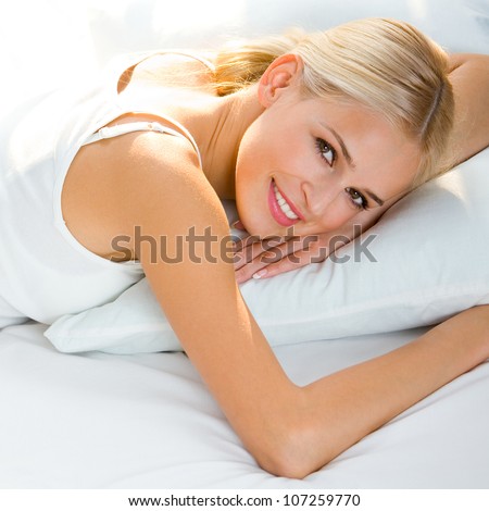 ... beautiful happy smiling blond woman waking up on bed - stock photo