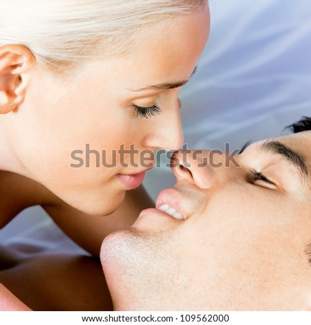 Young kissing cheerful attractive couple on bed