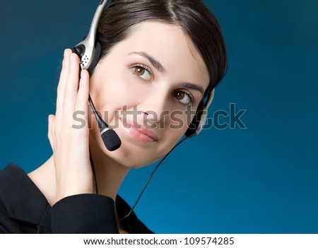 Portrait of happy smiling cheerful customer support phone operator in headset, over blue background