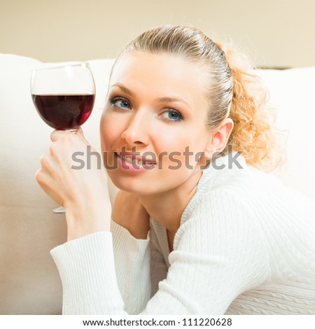 Portrait of young happy smiling cheerful beautiful blond woman with glass of red wine