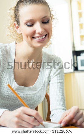 Young beautiful blond woman studying with notebook or organiser, indoors