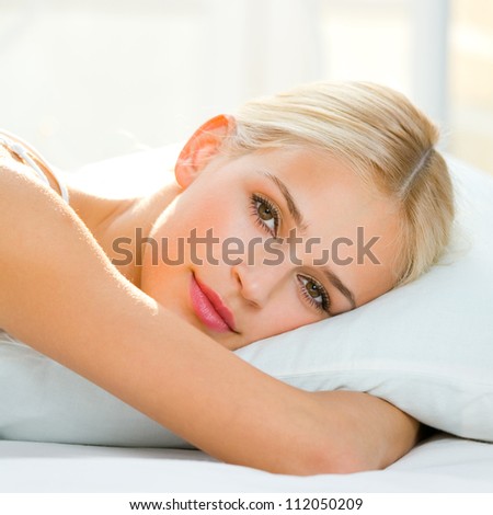 Young beautiful happy smiling blond woman waking up on bed