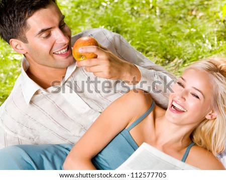 Young happy smiling cheerful couple reading together newspaper, outdoor