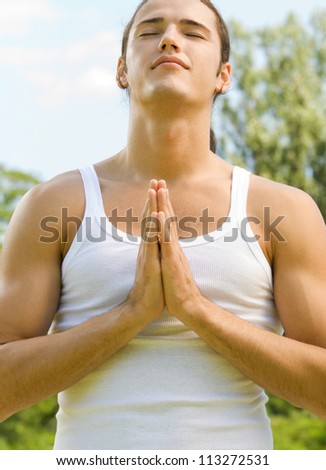 Young man meditating or praying, outdoor