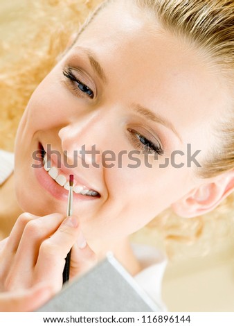 Cheerful smiling woman applying lipstick