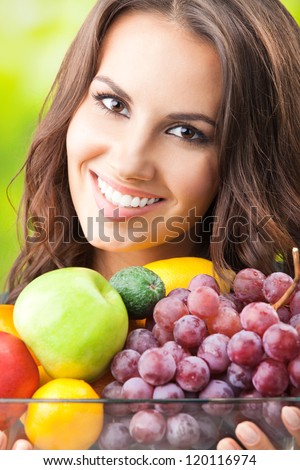 Young happy smiling woman with plate of fruits, outdoors, with copyspace for text or slogan.