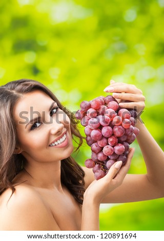 Young happy smiling woman with grapes, outdoors, with copyspace for text or slogan