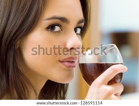 Portrait of young happy smiling cheerful beautiful woman with glass of red wine