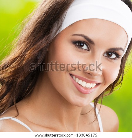 Portrait of happy smiling young beautiful woman in fitness wear, outdoors