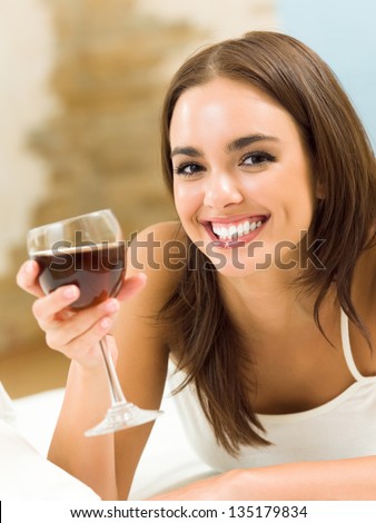 Portrait of young happy smiling cheerful beautiful woman with glass of red wine