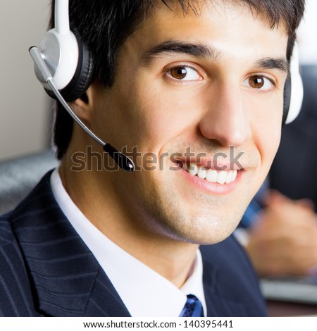 Portrait of happy smiling support phone operator in headset at workplace